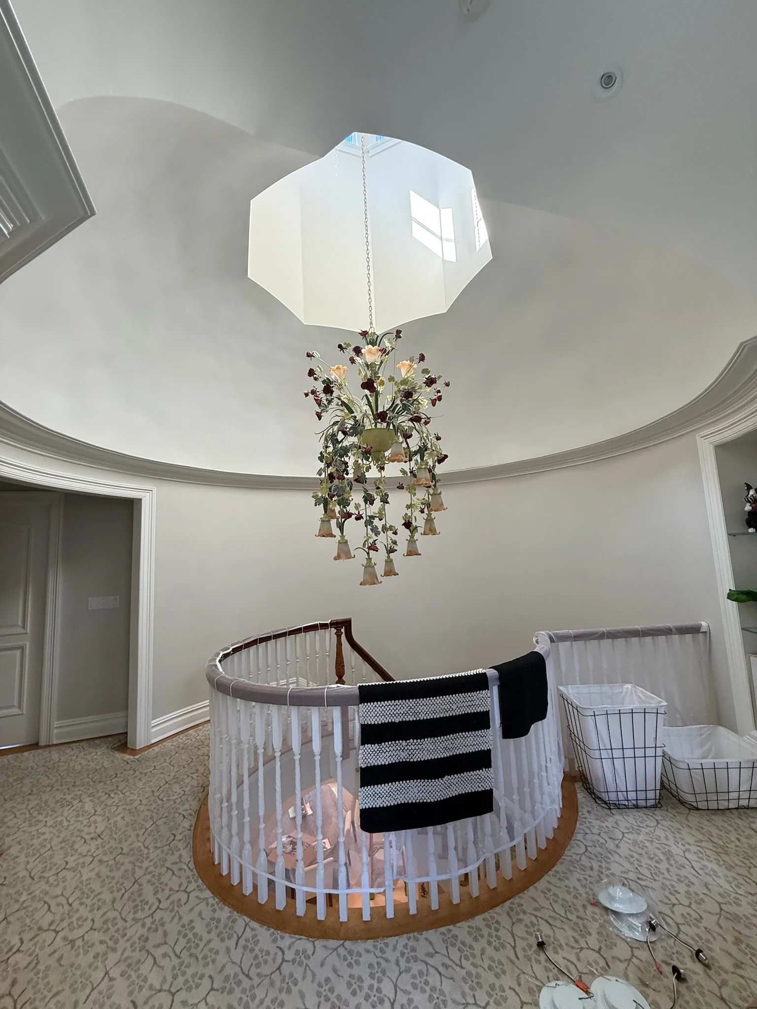 Octagonal skylight with hanging floral pendant fixture in nursery with circular crib