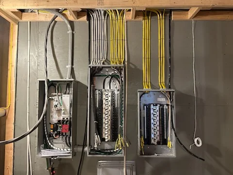 Electrical panel upgrade with multiple breaker boxes, organized yellow and white wire bundles, and conduit routing