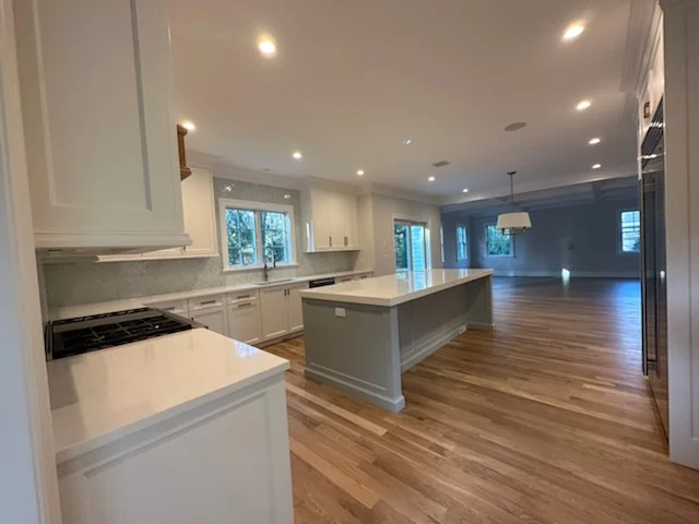 Recessed ceiling lights in white kitchen with island and hardwood floors