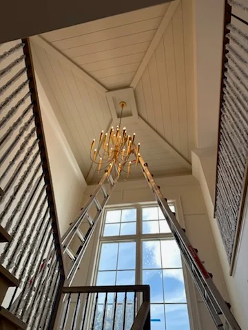 Brass chandelier hanging in two-story foyer with vaulted ceiling and shiplap walls