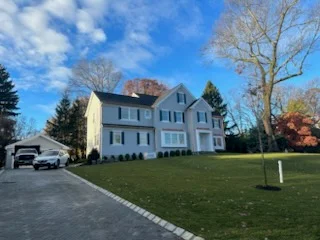 Two-story colonial home with newly installed driveway lighting and paved entrance