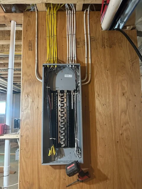 Electrical panel with breakers, yellow and white Romex cables organized and routed into service box